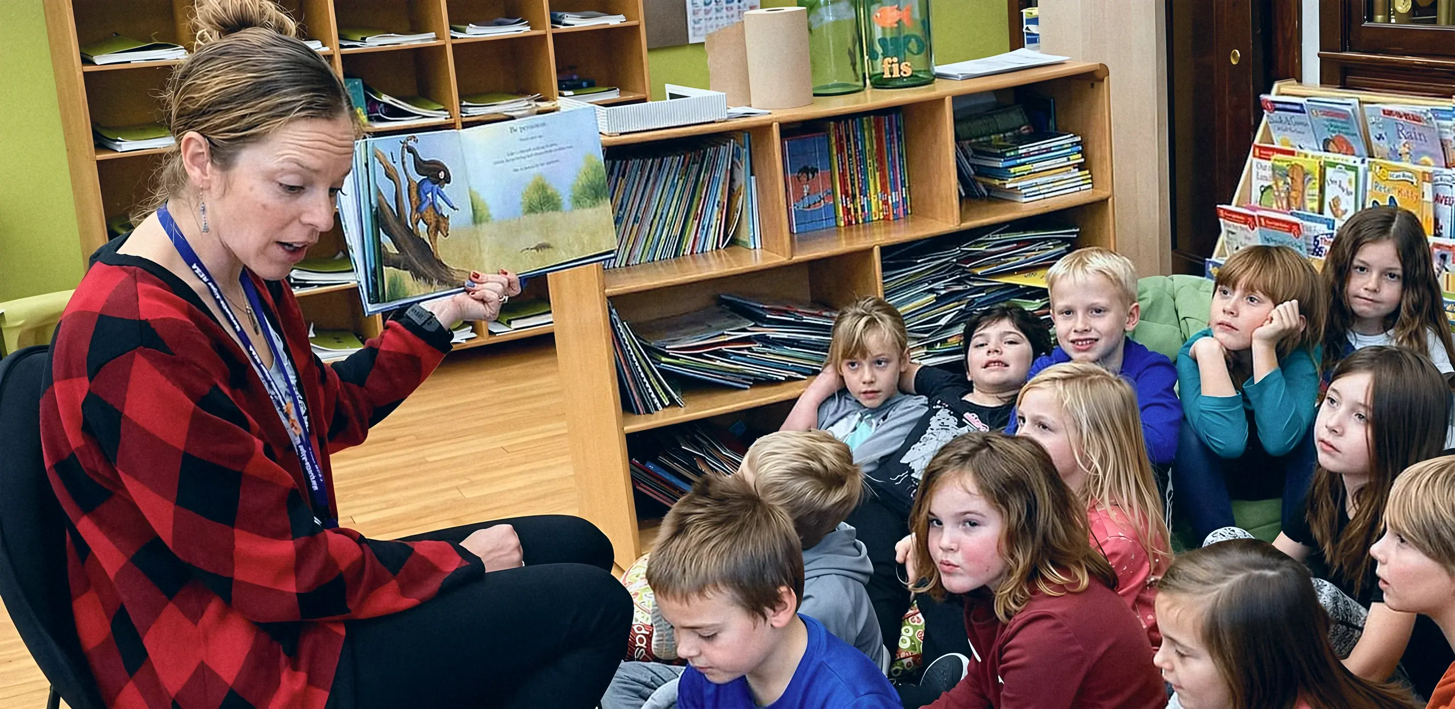 Teacher reading to a class of engaged young students in a school library