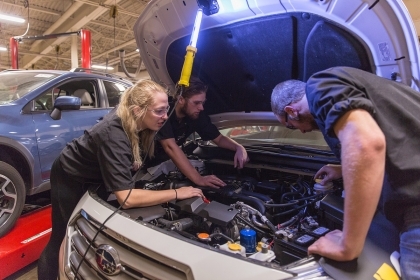 Students working on engine of vehicle