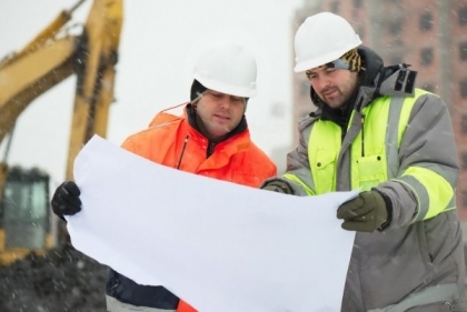 Two workers inspecting paper blueprints on the jobsite