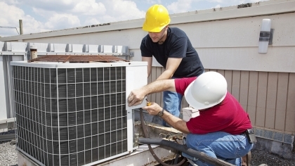 Two techs working on roof mounted AC unit