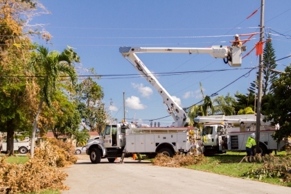 A boom lift truck with a person in the basket, inspecting an electrical line