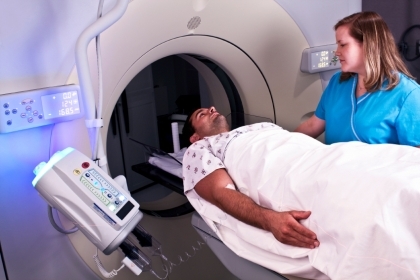 A patient entering an MRI machine with the assistance of a nurse or technician